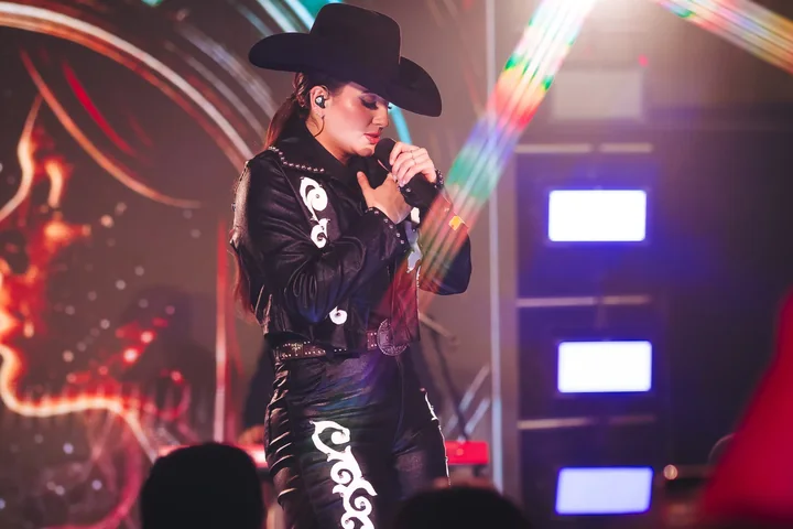 Clara Faria cantando com chapéu preto